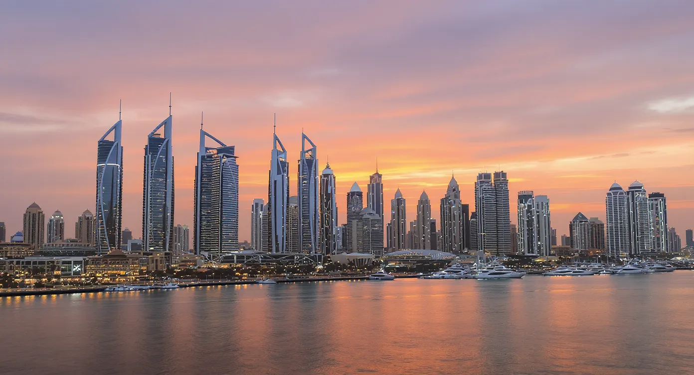 Skyline view of Dubai Marina at dusk with high-rise residential towers illuminated, showcasing growth in the real estate sector that attracts international investors