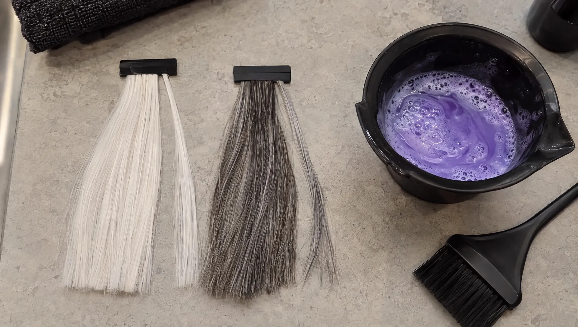 White and salt-and-pepper hair swatches sit beside violet shampoo for a small gray-hair strand test.