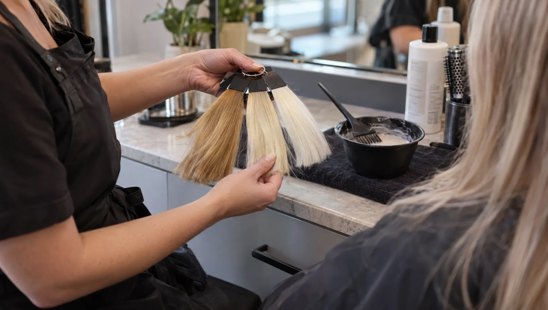 A colorist compares golden, pale yellow, and near-white hair swatches beside a tint bowl when planning platinum blonde.