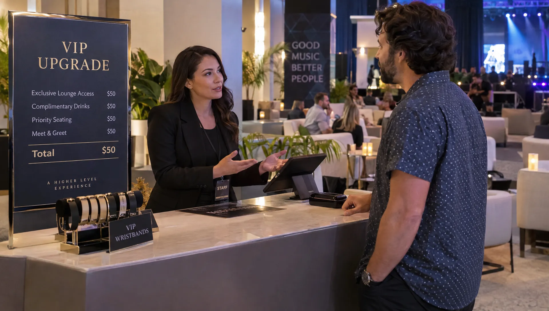 Landscape medium eye-level scene at a hospitality counter inside a venue: an adult organizer calmly explains a VIP upgrade price to an adult attendee, with both people fully visible and engaged in conversation. A wristband display and lounge seating establish the premium event setting, while the counter remains secondary to the interaction.