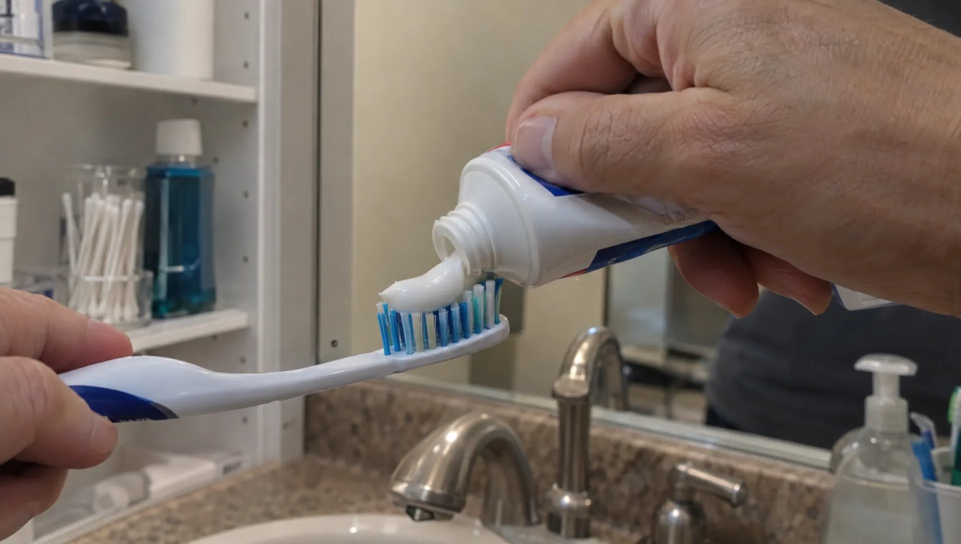 A hand squeezes toothpaste from a small tube beside a bathroom sink, showing why toothpaste counts as a liquid-category item in hand luggage.