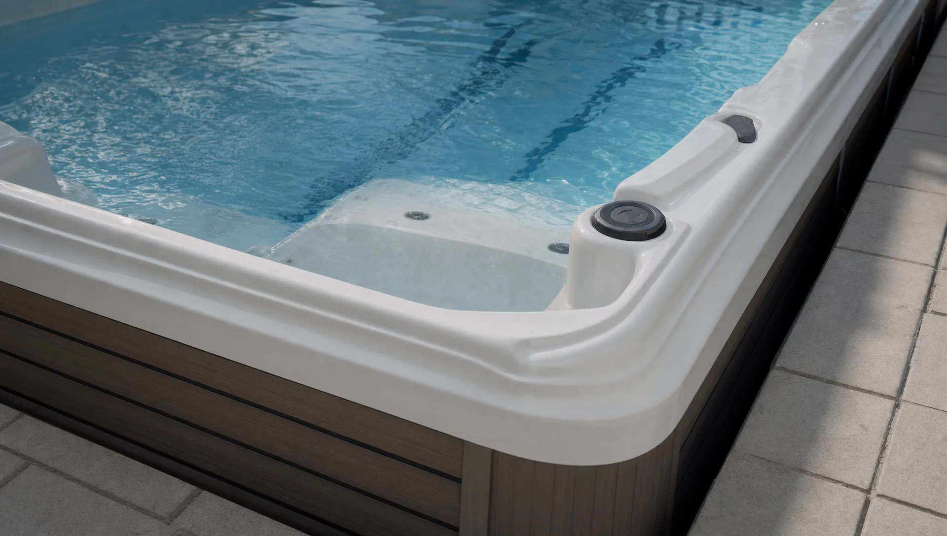 Swim Spas vs Lap Pools for Home Swimming — Wellness | Hearthside Supply LLC Blog Close-up of a swim spa corner showing the waterline, seating and step-in area in a backyard setting.