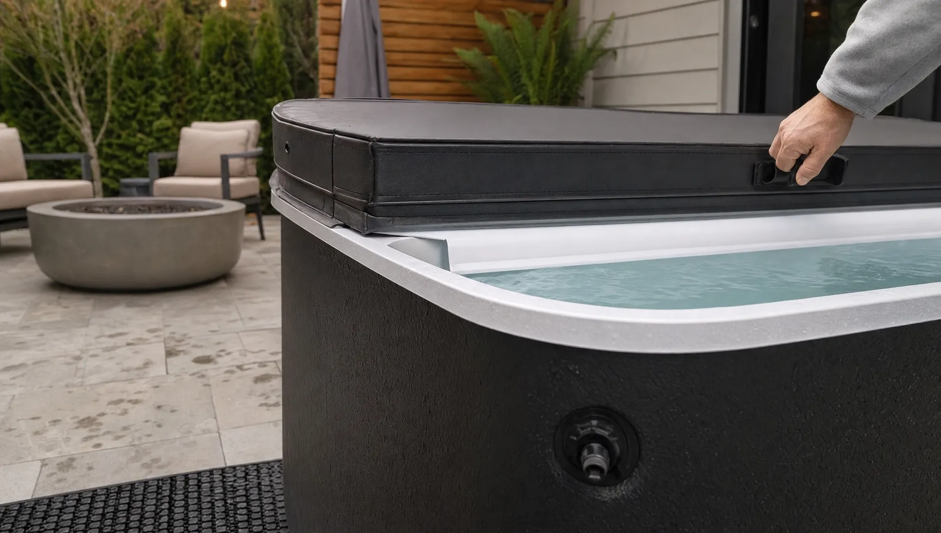A close-up shows the waterline and drain area of a cold plunge tub on a patio.