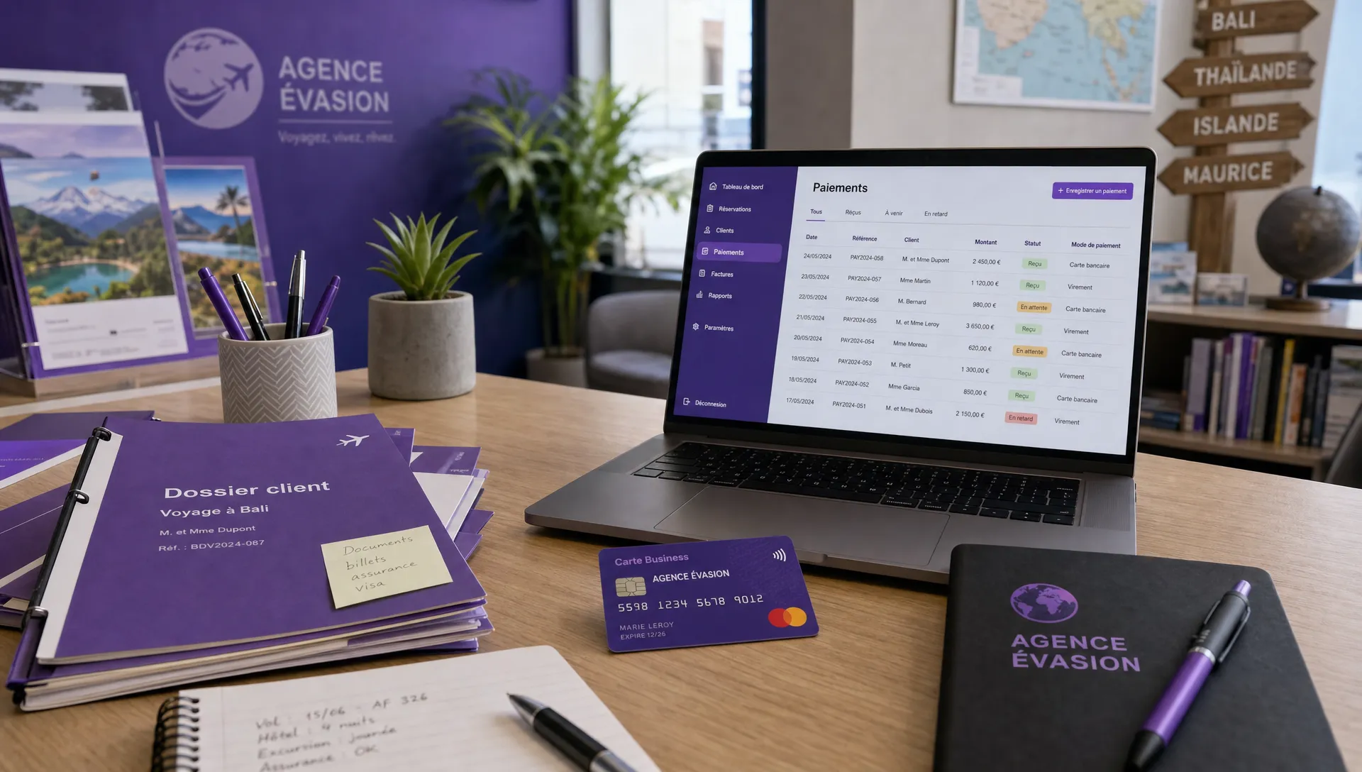 Table de travail d’une petite agence de voyage avec dossiers clients, carte bancaire professionnelle et ordinateur affichant des paiements organisés.