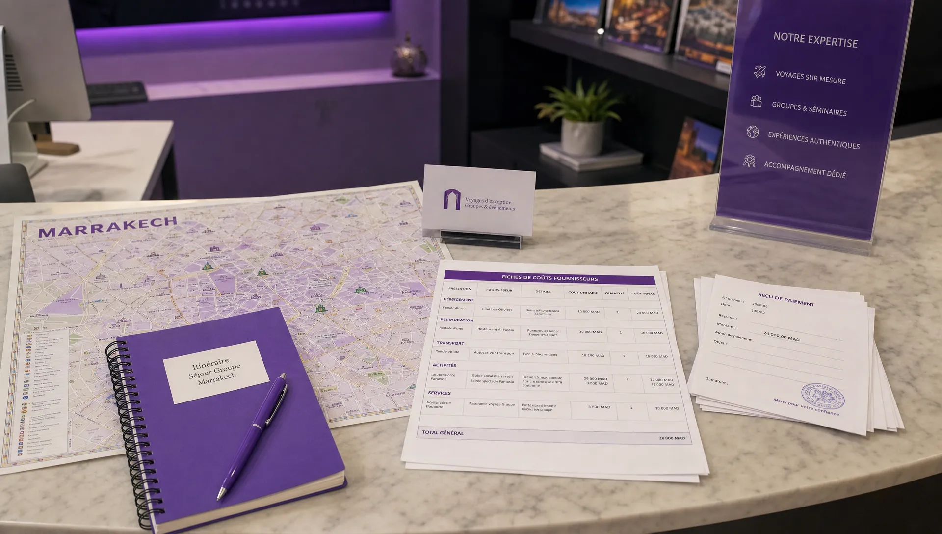 Un comptoir d’agence montre une carte de Marrakech, un carnet d’itinéraire, des fiches de coûts fournisseurs et des reçus de paiement pour préparer un séjour de groupe.
