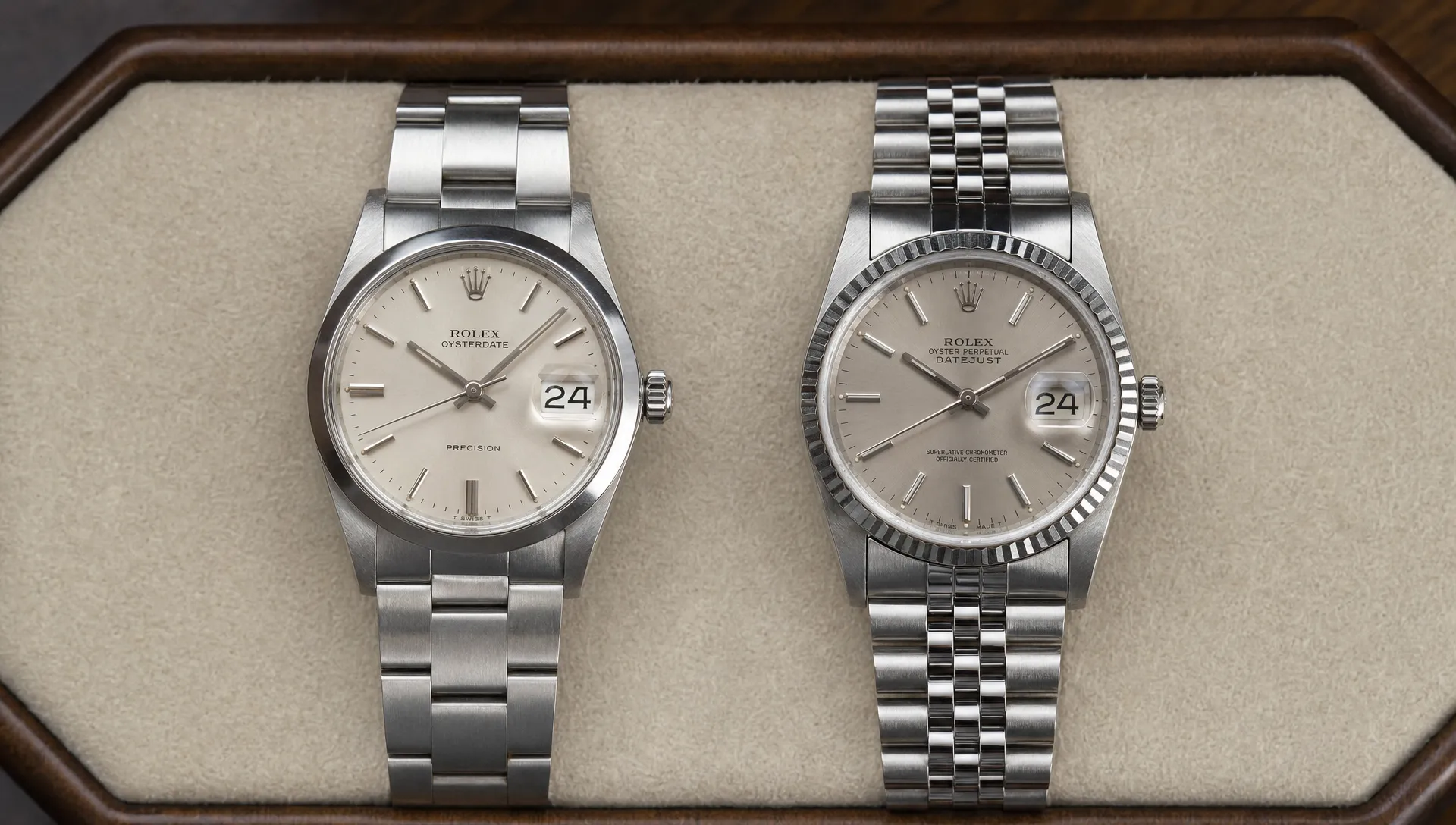 A 34mm Oysterdate Precision and a 36mm Datejust rest side by side on a watch tray with their dials, case edges, clasps and steel bracelets visible.