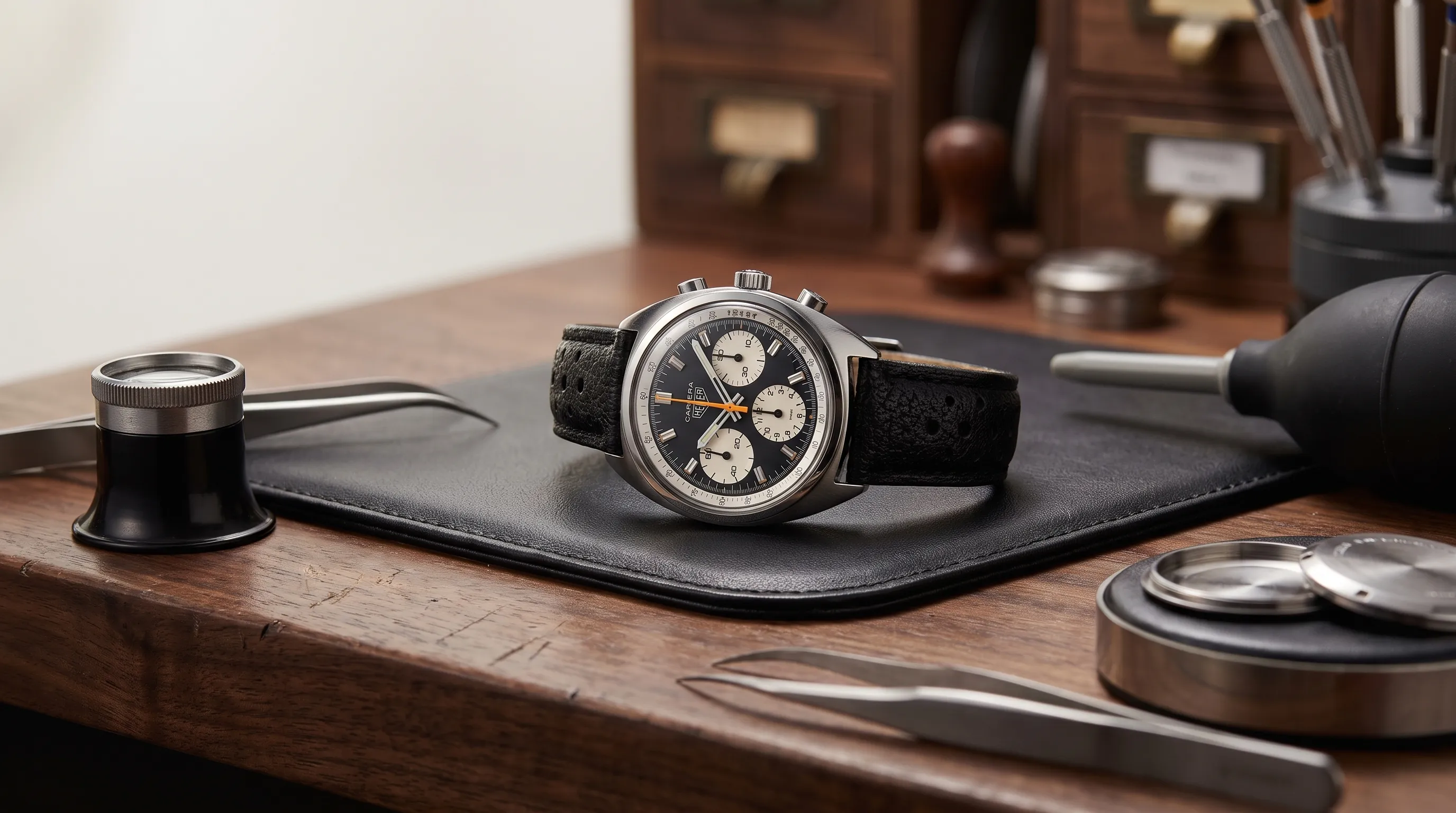 A vintage Omega Seamaster rests on a watchmaker’s bench with tools arranged around it.