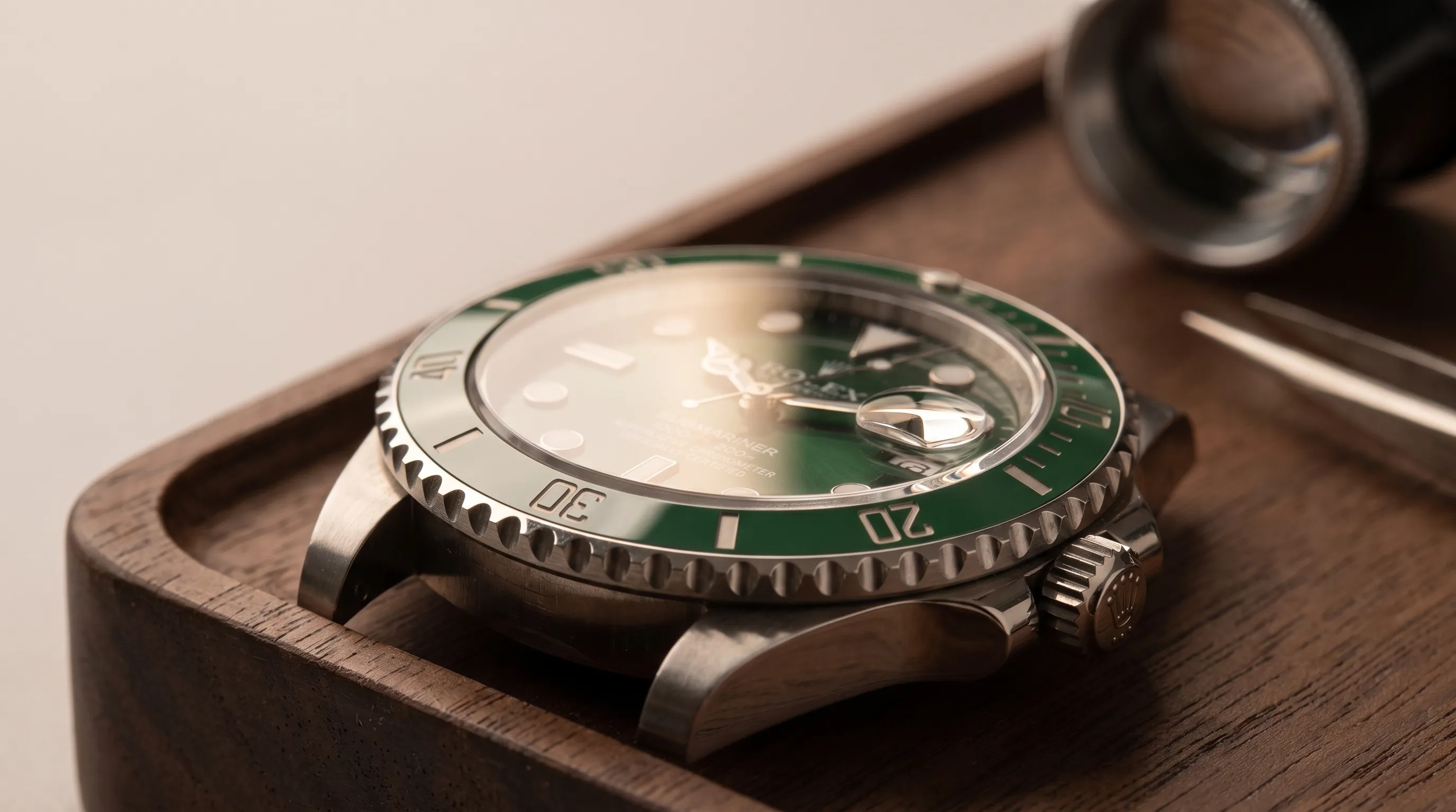 Extreme close-up of a Rolex Submariner Hulk on a watchmaker’s bench, showing the green ceramic bezel, crown side and green sunburst dial.