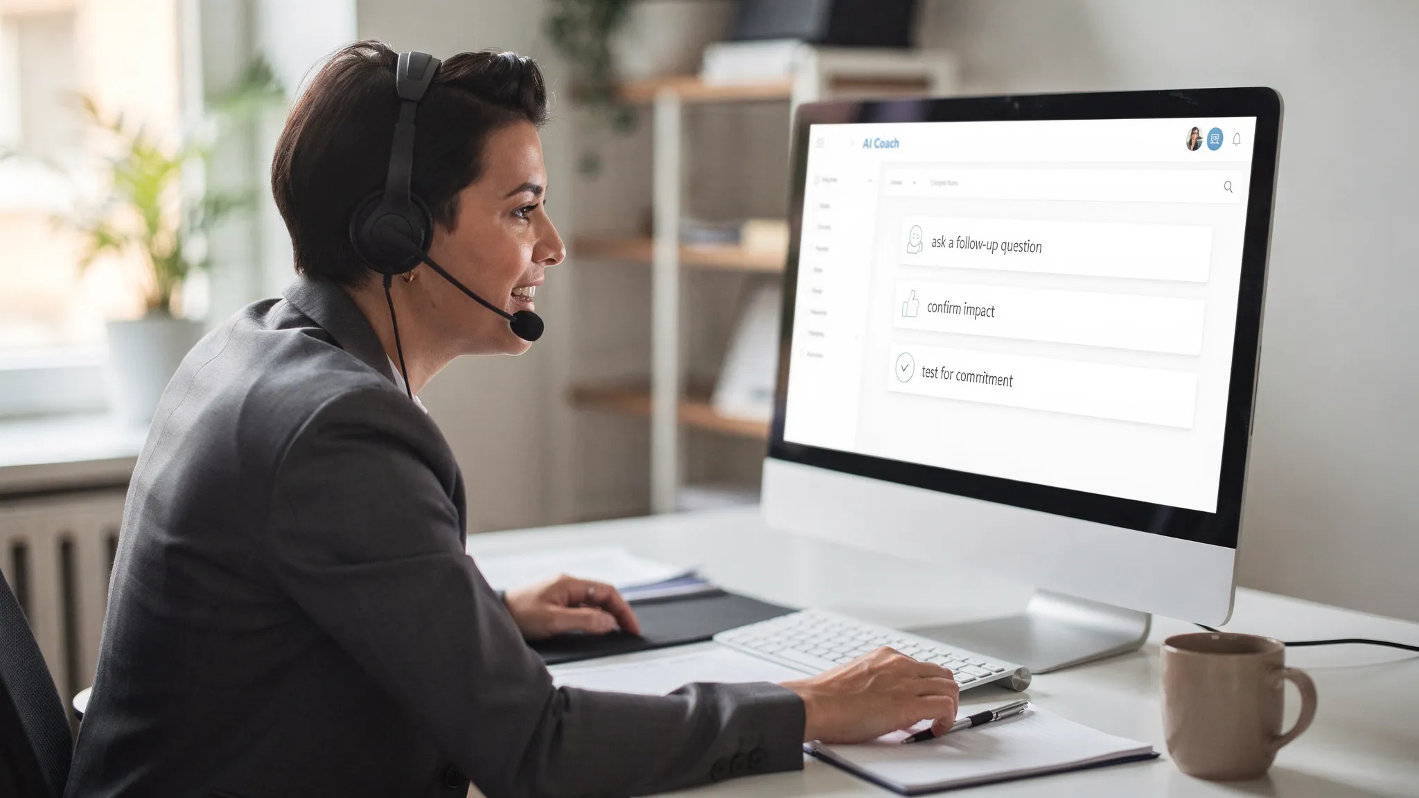 A salesperson practicing a roleplay sales call at a desk, speaking into a headset, while an AI coach panel provides real-time prompts like “ask a follow-up question,” “confirm impact,” and “test for commitment.” The screen is facing the viewer and shows only simple coaching cues, not brand logos.