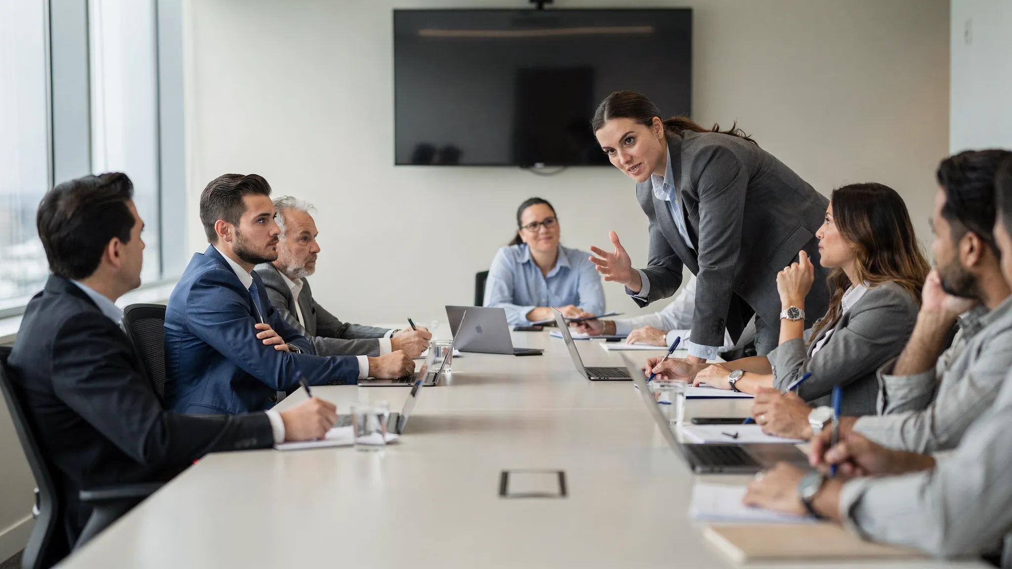 A sales team practicing objection handling in a modern training room, with one person roleplaying a skeptical buyer and another responding confidently while teammates observe and take notes.