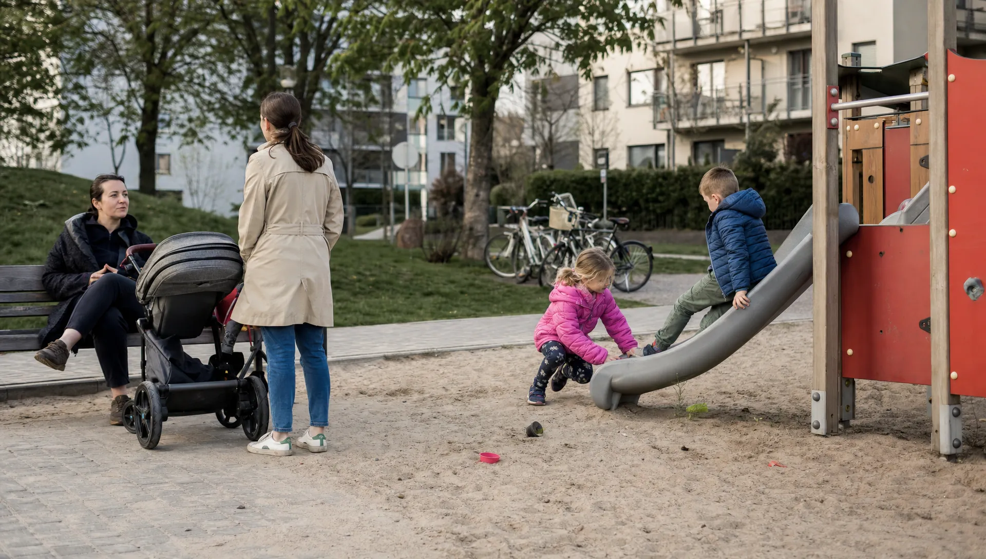 A British mother watches two children play in a Polish playground, showing an ordinary afternoon for families moving to Poland with children.