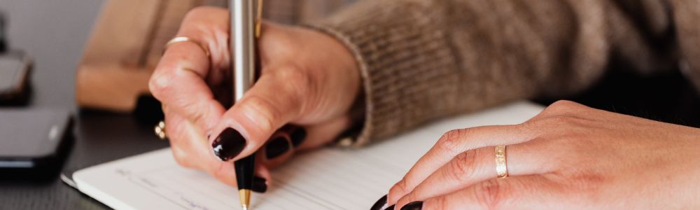 A weekly planner on a desk marks a protected lunch break and an evening work cutoff beside an open notebook, illustrating practical changes discussed in therapy for burnout.