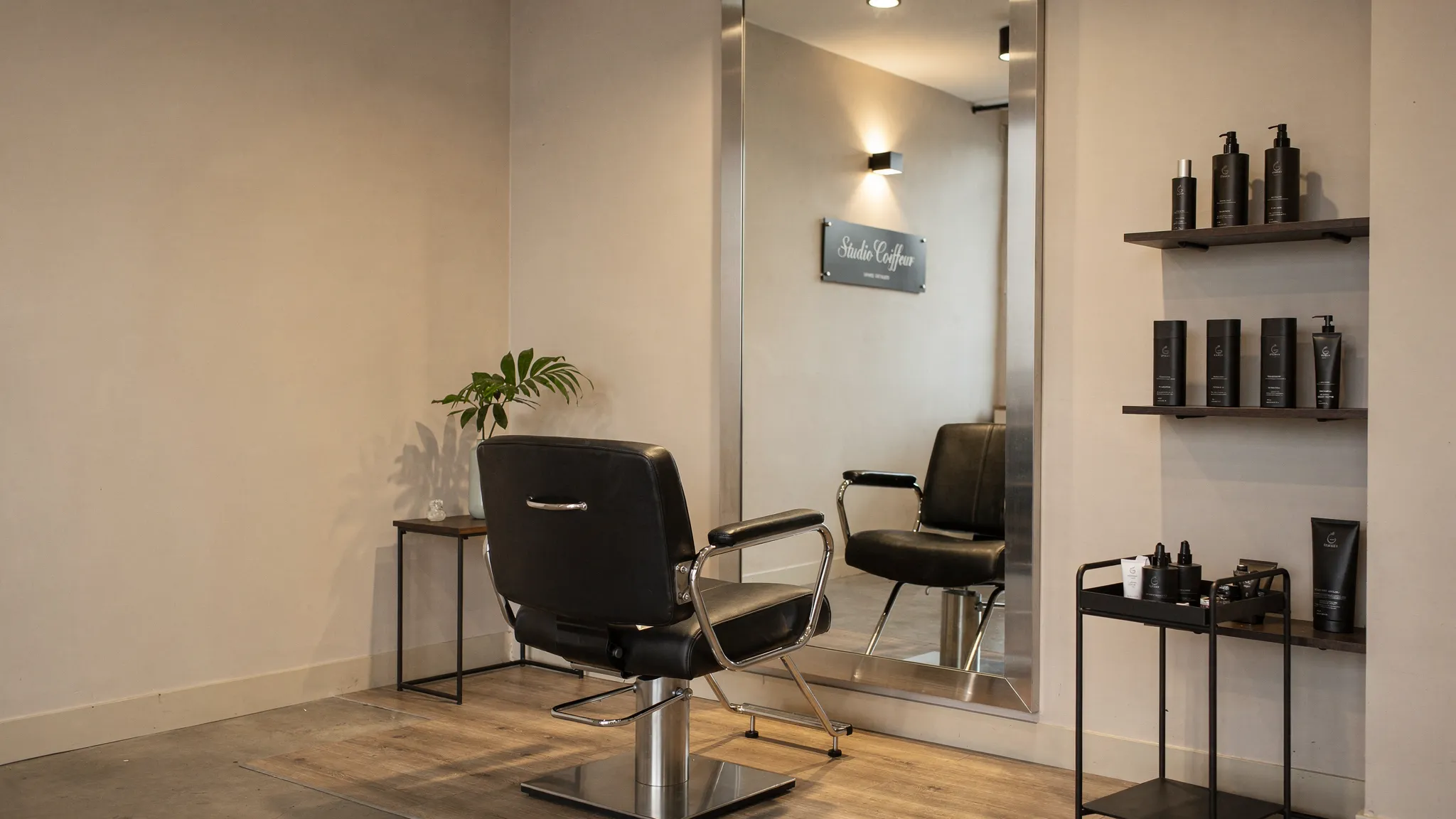 Un studio coiffeur premium avec fauteuil de coiffage, miroir élégant, éclairage chaleureux, espace propre et ambiance intimiste pensée pour une expérience client haut de gamme.