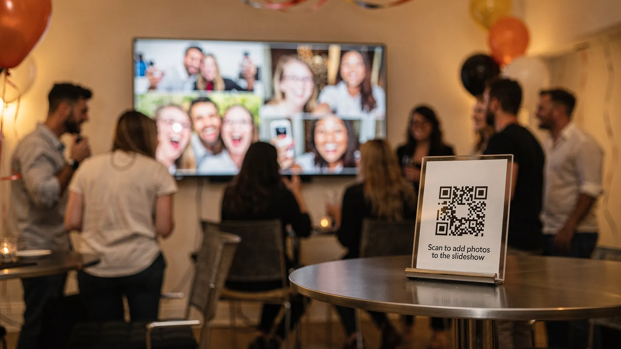 A party room with a TV showing a live slideshow of guest photos. In the foreground, a small sign on a stand displays a QR code with the text “Scan to add photos to the slideshow.” The TV screen content faces the guests.