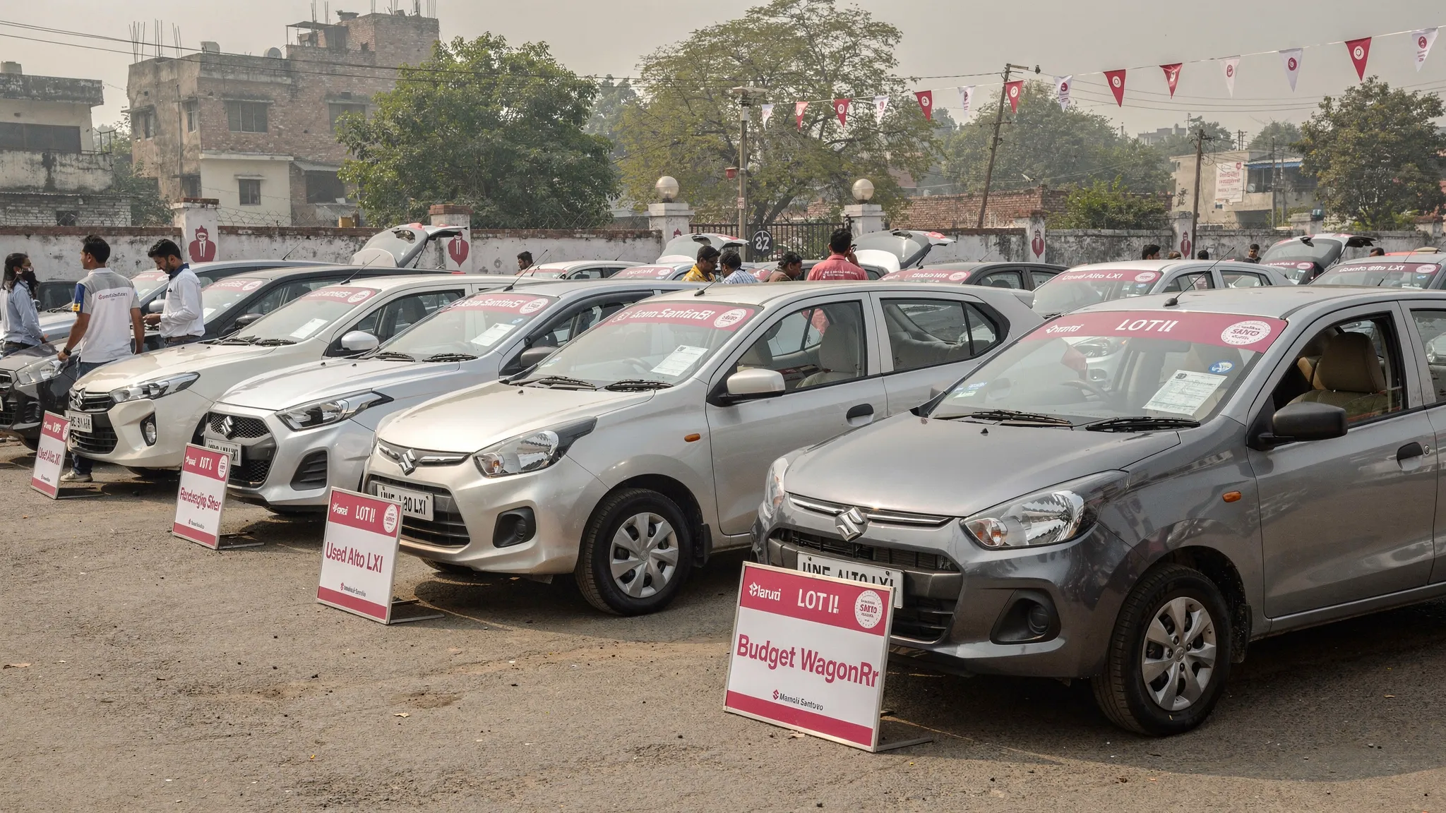 Compact used hatchbacks parked at a Delhi NCR used car lot, with small budget cars such as Alto, WagonR and Santro lined up for inspection.