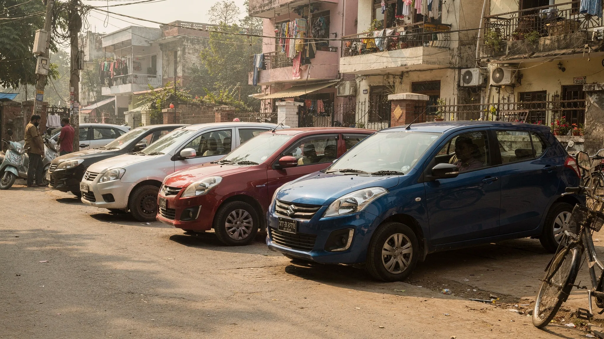 A lineup of budget-friendly hatchbacks parked on a typical Indian residential street, showing compact dimensions, practical design, and everyday city-use context.