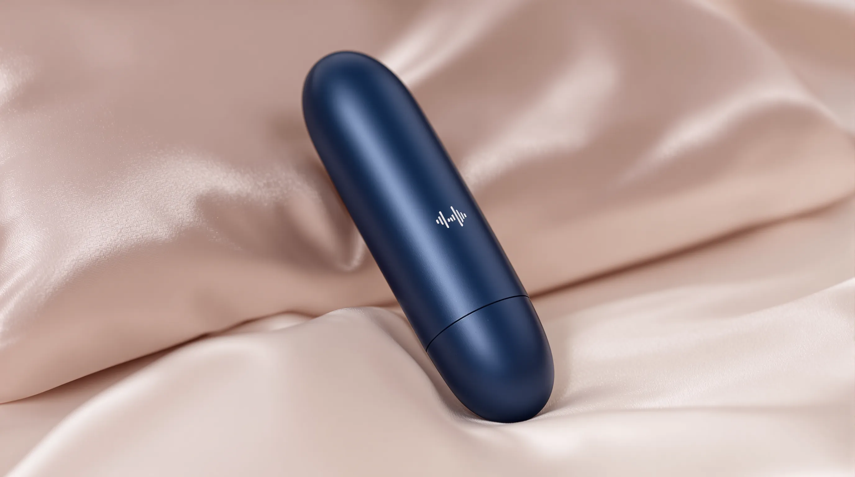 Close-up of a sleek navy blue bullet vibrator resting on a folded silk pillow, with a sound wave graphic indicating low decibel output.
