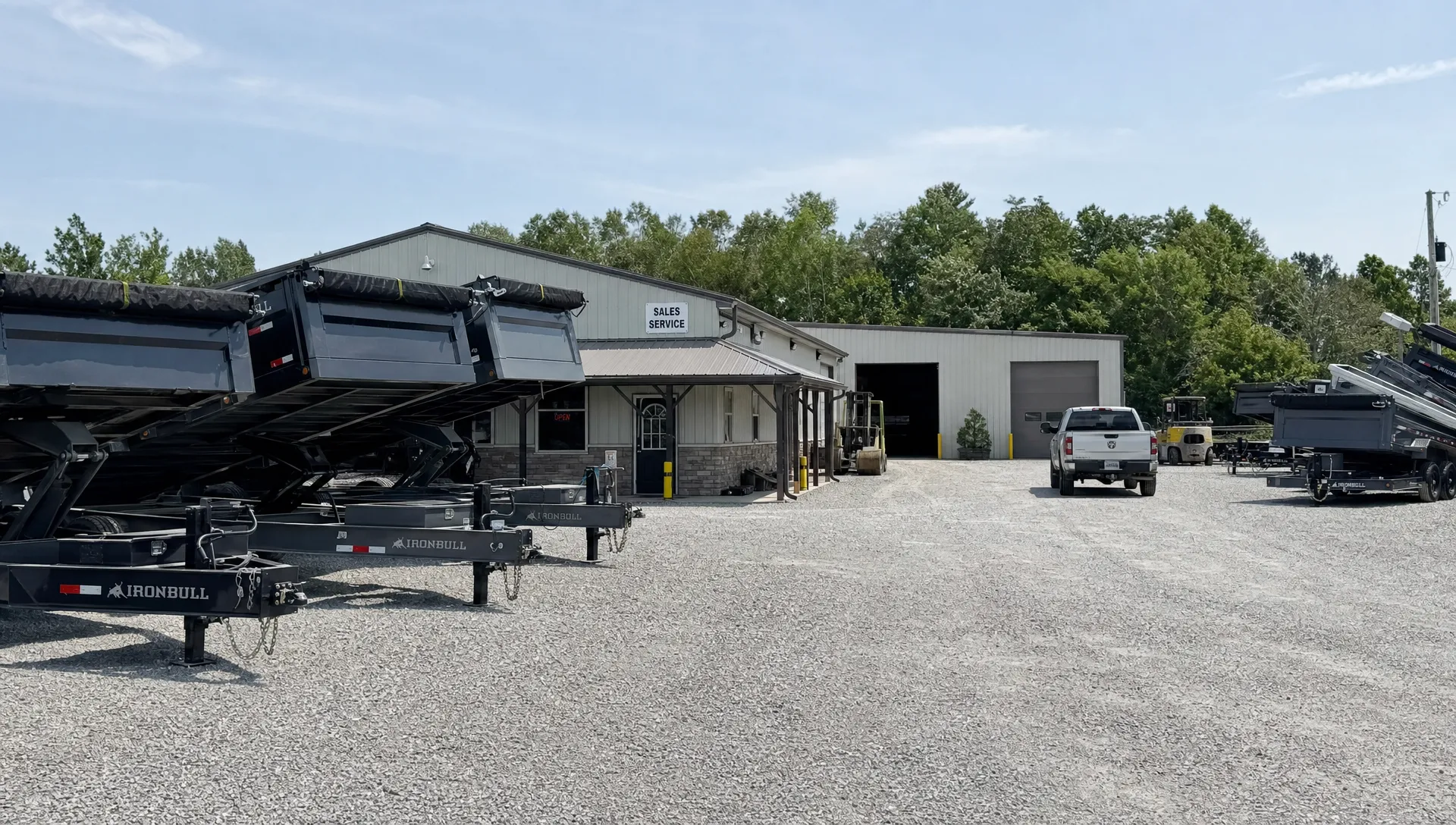 Rows of dump trailers line a dealership lot beside the office and service bay. Rows of dump trailers line a dealership lot beside the office and service bay.