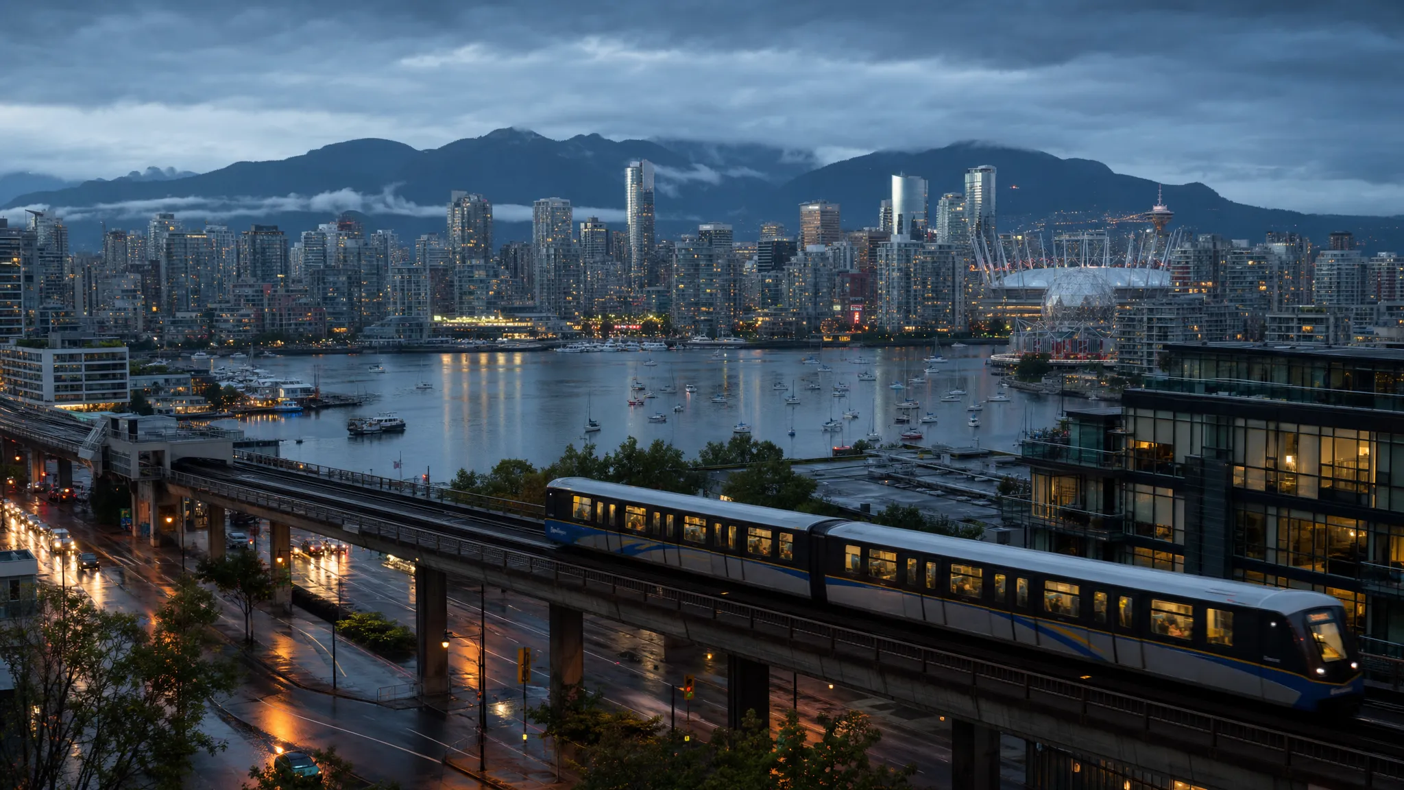 A rainy evening view of Vancouver with downtown towers, False Creek water, mountain silhouettes, and a SkyTrain line showing how geography and transit shape hotel choices.