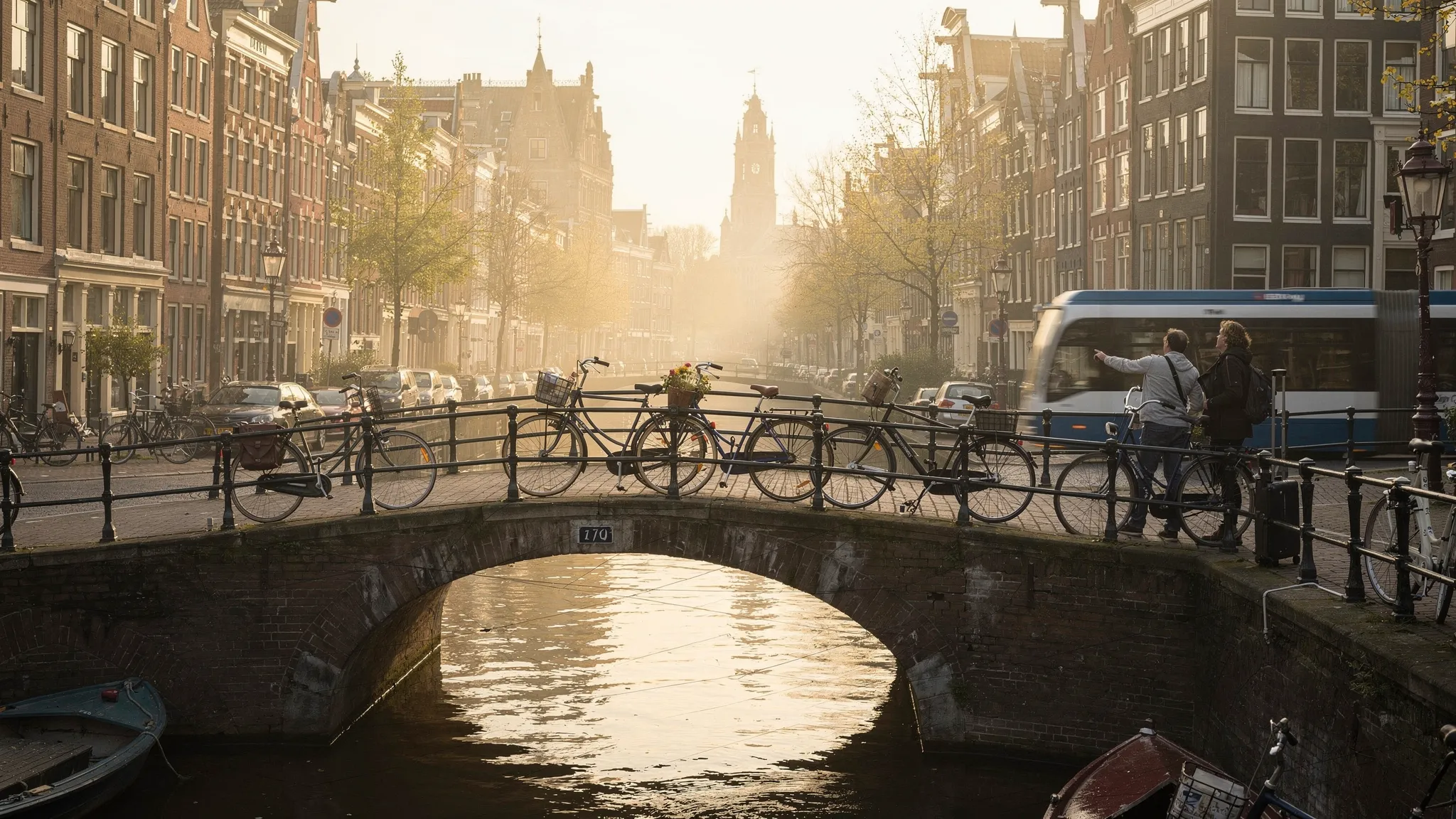 A quiet Amsterdam canal at morning with bicycles on a bridge, narrow canal houses, a tram in the distance, and travelers with luggage deciding between the historic center and modern districts.