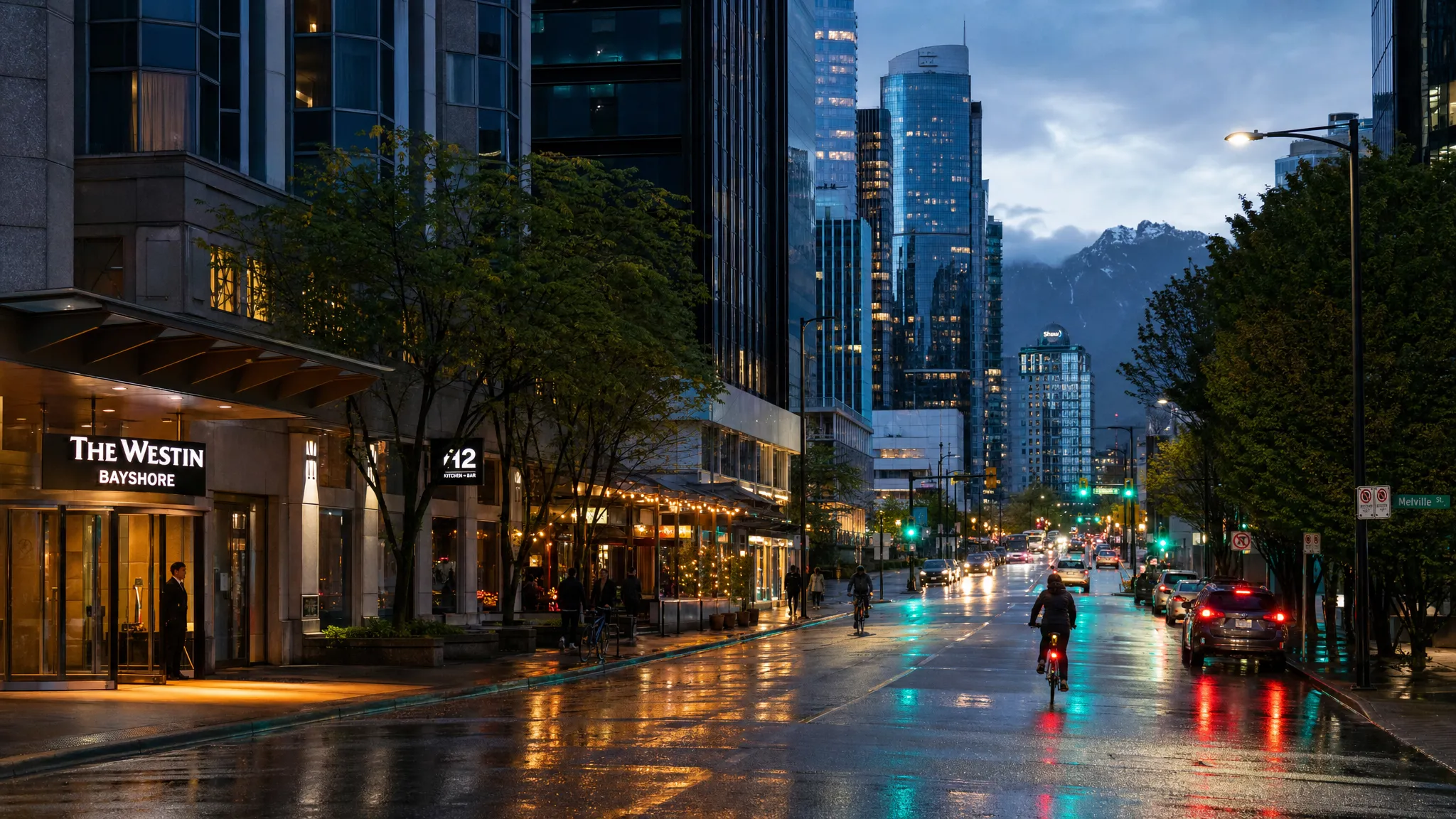 A rainy evening street scene in Vancouver with hotel entrances, glowing restaurant windows, cyclists, and distant glass towers reflecting mountain silhouettes beyond the downtown skyline.
