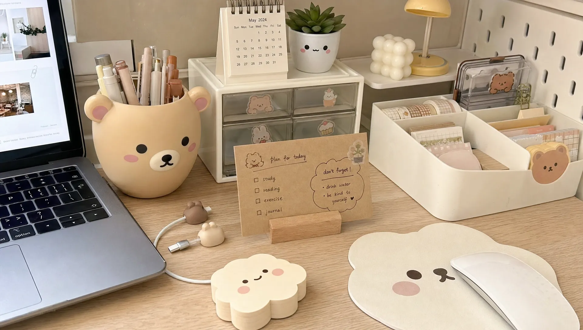 A tidy home office desk with kawaii desk accessories, including a bear-shaped pen holder, cloud sticky notes, a mouse pad, mini drawers, cable clips and a handmade planner card.