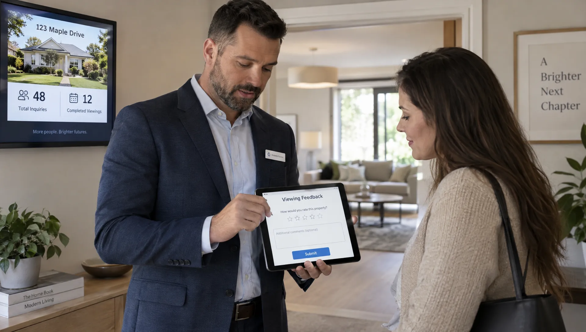 In a property viewing room, an adult real estate agent stands beside a prospective buyer after a tour, entering feedback on a tablet held at chest height with its screen facing the camera. A doorway opens onto the viewed living space behind them, and a small wall display shows the listing campaign's inquiry and completed-viewing totals.