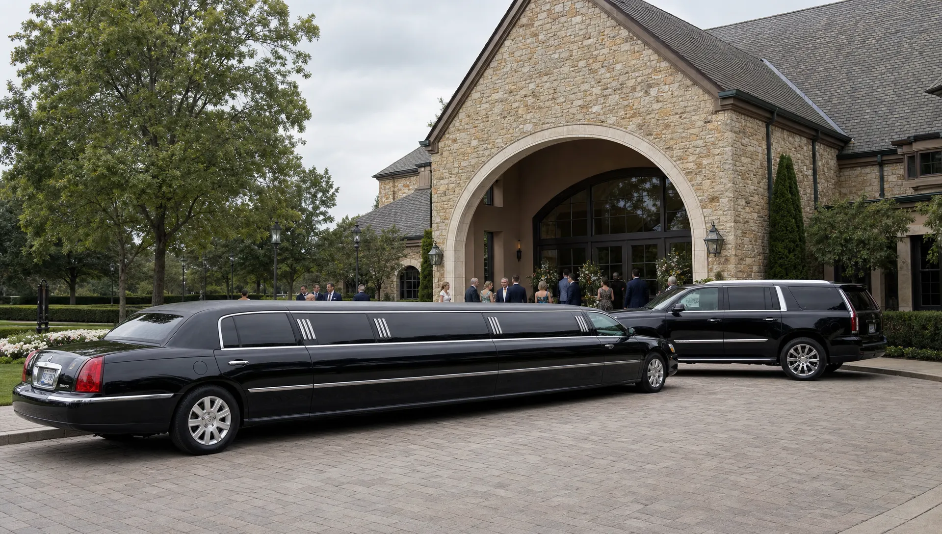 A stretch limousine and executive SUV wait outside a wedding venue entrance as guests arrive for the event.