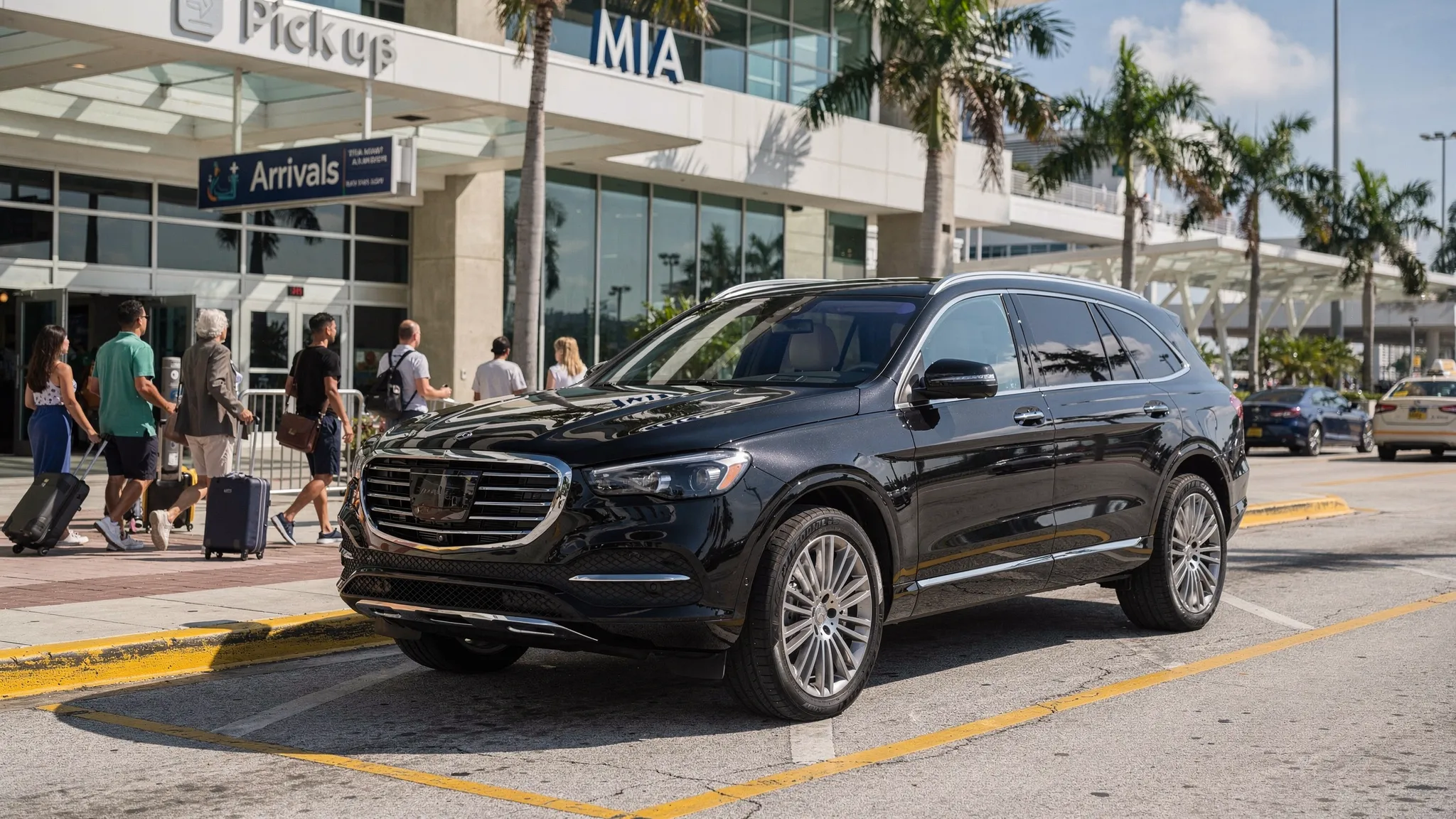 A black luxury SUV waiting in a designated airport pickup area outside Miami International Airport while travelers with luggage approach from the terminal doors.