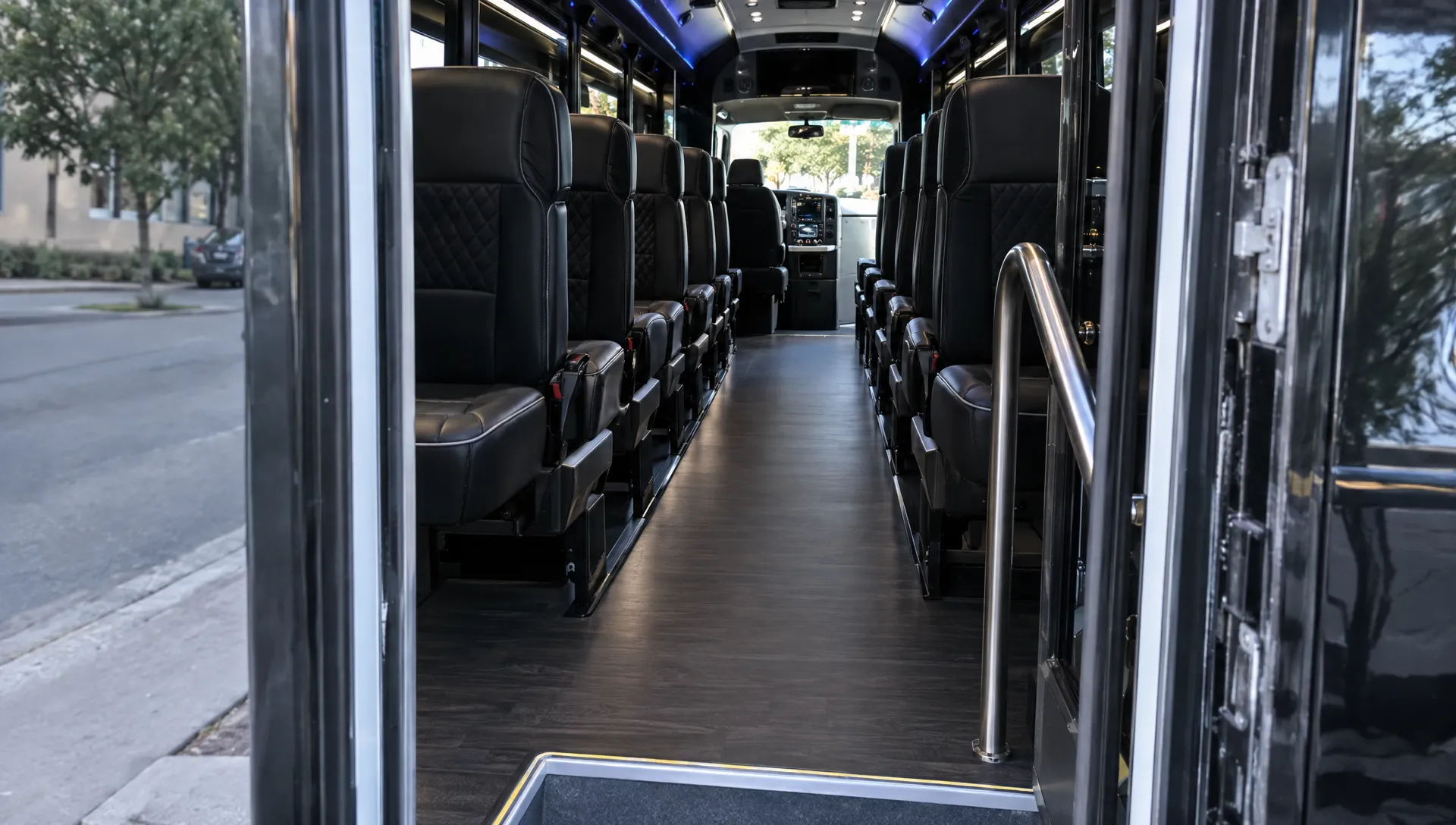 The open entry of a 22-passenger party bus reveals upholstered seating, a handrail and a clear center aisle.