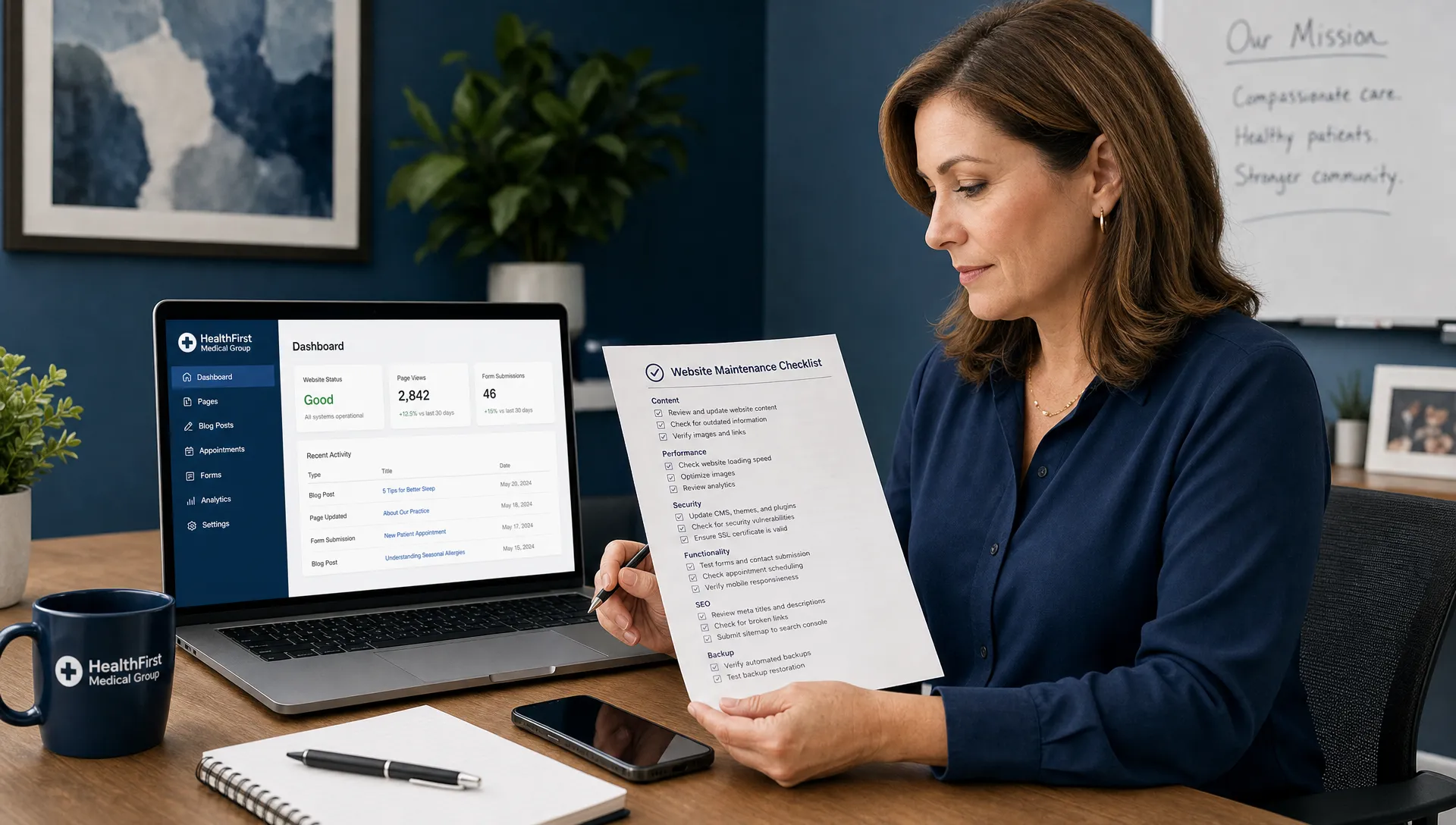 A healthcare practice manager reviewing a website maintenance checklist beside a laptop and phone, with the laptop screen facing forward and showing a simple website dashboard layout.