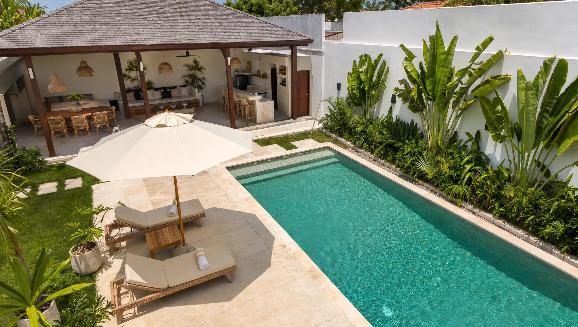 Private outdoor lounge and pool area at luxury home rentals with shaded seating, dining space, and a quiet walled garden, seen from an elevated corner looking across the full yard.