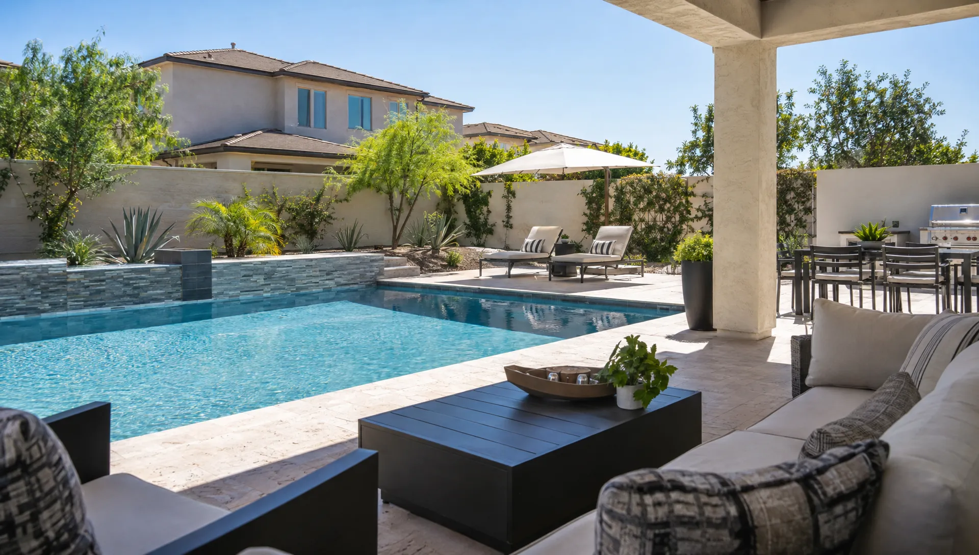 A Scottsdale vacation home's pool courtyard shows shaded seating, boundary walls, and neighboring windows.