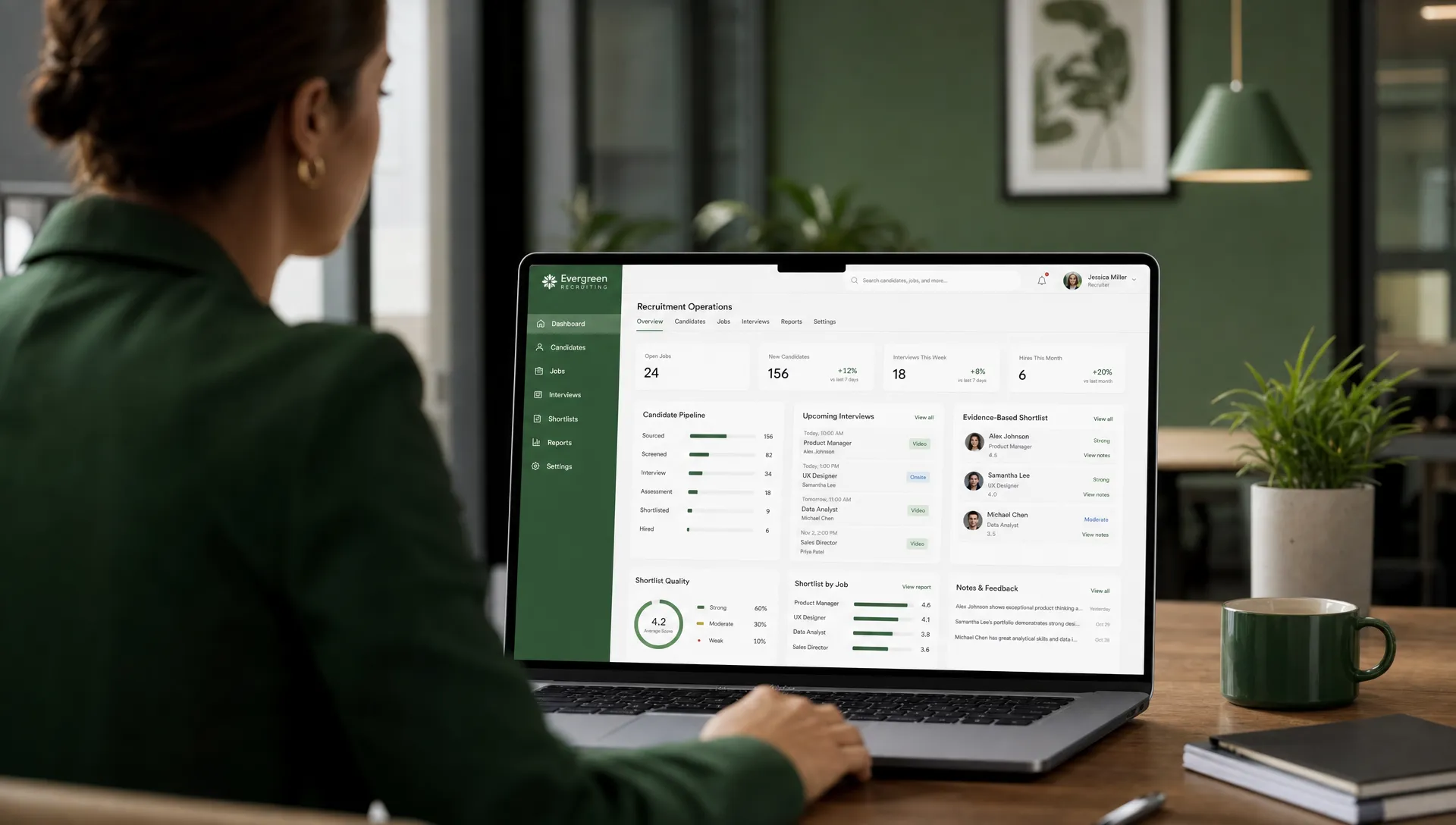 A professional recruitment operations workspace with a recruiter reviewing candidate cards, interview schedules, and evidence-based shortlist notes on a laptop screen facing the recruiter with the interface oriented correctly.