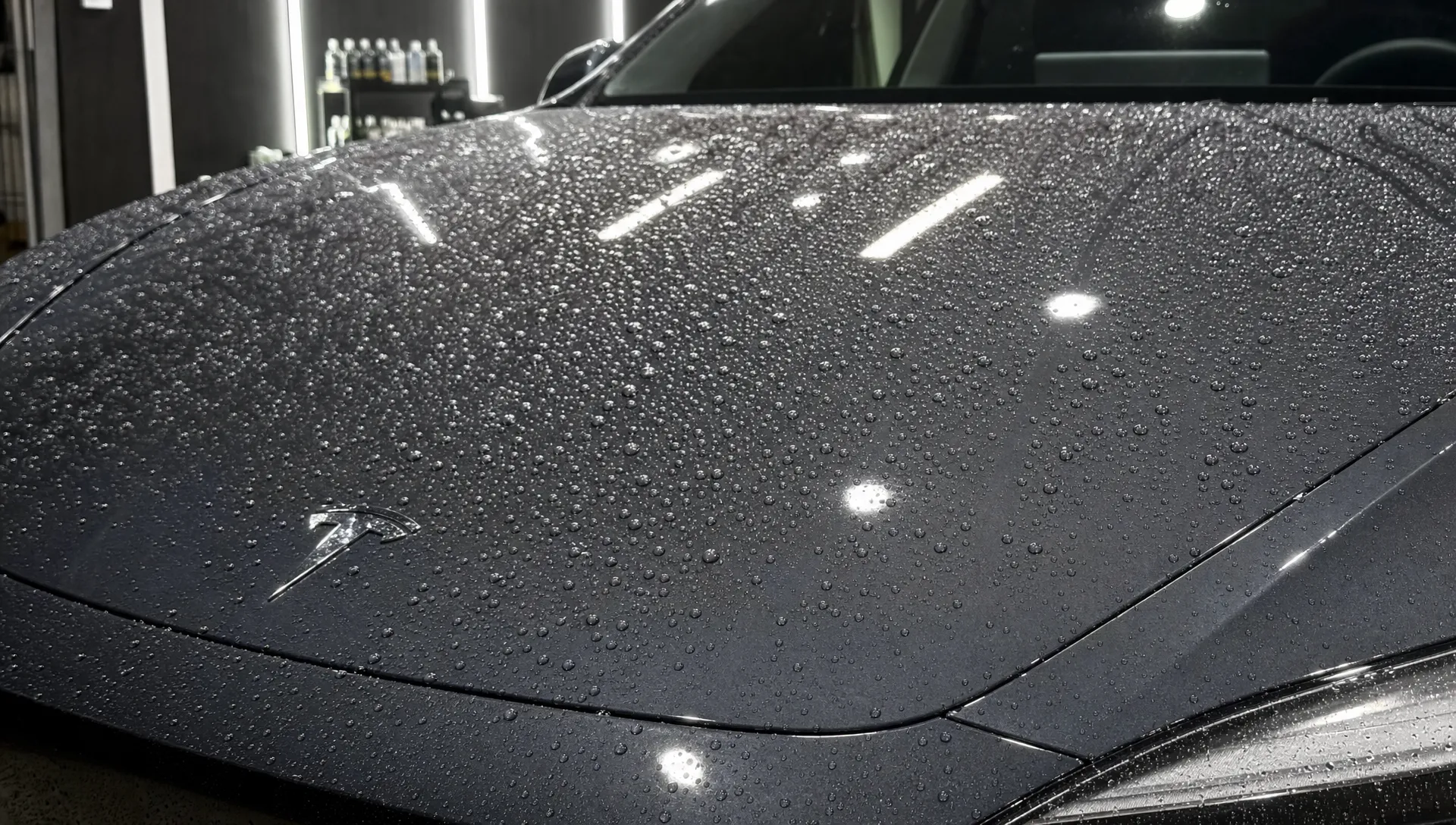 A close view of a wrapped car bonnet with water beads on the vinyl surface, showing ceramic coating protection after application.