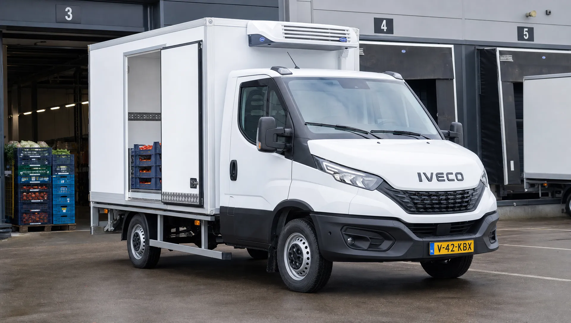 Een IVECO Daily koelwagen bij een distributiecentrum met geopende zijdeur, geïsoleerde laadruimte, kratten en een elektrische koelunit.