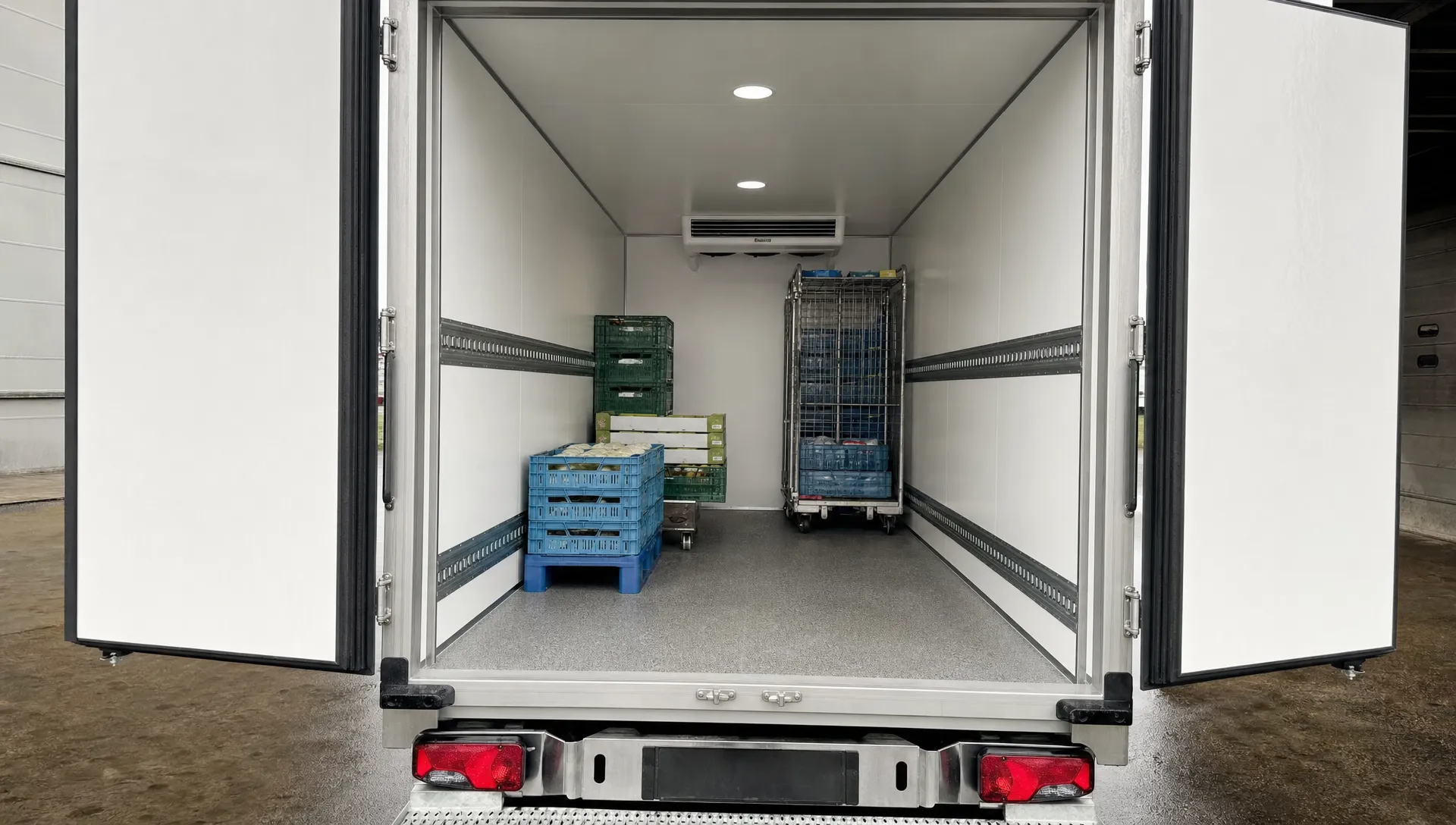 De laadruimte van een koelopbouw met achterdeuren open, isolatie, antislipvloer en ruimte voor kratten en rolcontainers.